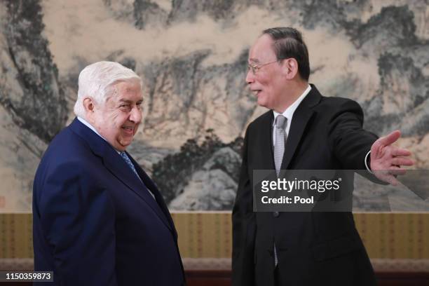 Syria's Foreign Minister Walid Al-Moualem is greeted by Chinese Vice President Wang Qishan before a meeting at the Zhongnanhai leadership compound in...