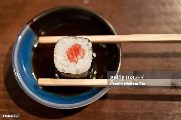 tuna maki sushi with chopsticks in soy sauce - soy sauce stock pictures, royalty-free photos & images