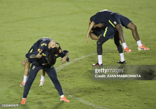 Brazil's footballers defender Fagner, midfielder Philippe Coutinho, defender Miranda and midfielder Willian stretch during the official training...