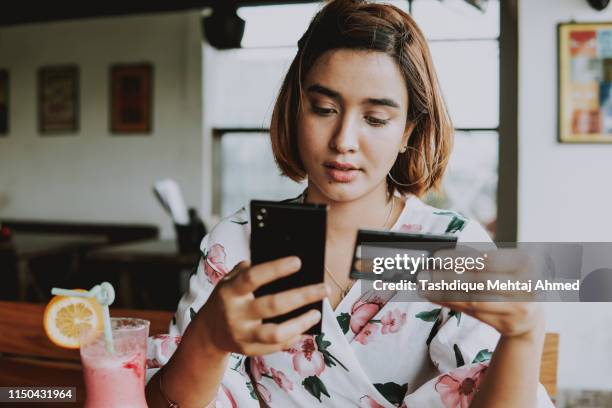 young woman shopping online with smartphone and credit card on hand. - internet banking stock pictures, royalty-free photos & images