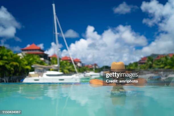 rear view woman relaxing in swimming pool of luxury island - private beach stock pictures, royalty-free photos & images