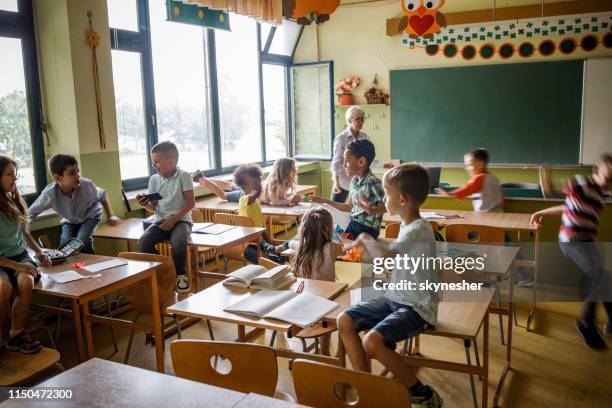 grande grupo de estudantes elementares que têm o divertimento em uma classe na sala de aula. - elementary age - fotografias e filmes do acervo