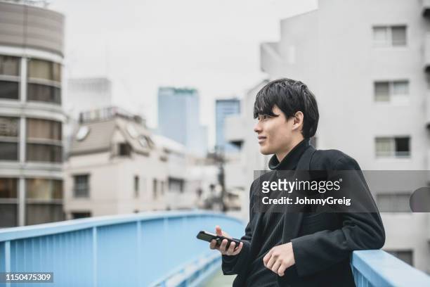 portrait of handsome young japanese man holding phone - polo neck stock pictures, royalty-free photos & images