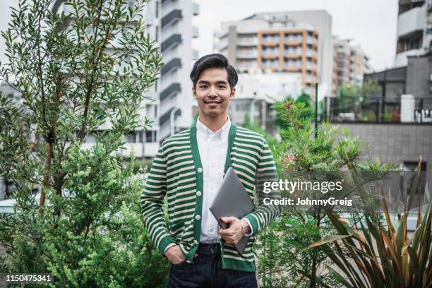 portrait of japanese man in striped cardigan carrying laptop - japanese brush stroke stock pictures, royalty-free photos & images