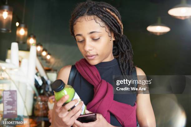 young woman examining label of juice bottle - information nutritionnelle photos et images de collection