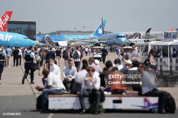 Attendees walk between passenger aircraft on display during the 53rd International Paris Air Show at Le Bourget, in Paris, France, on Tuesday, June...