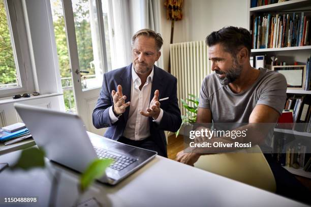 businessman and casual man sitting at desk with laptop - beratungsgespräch stock-fotos und bilder