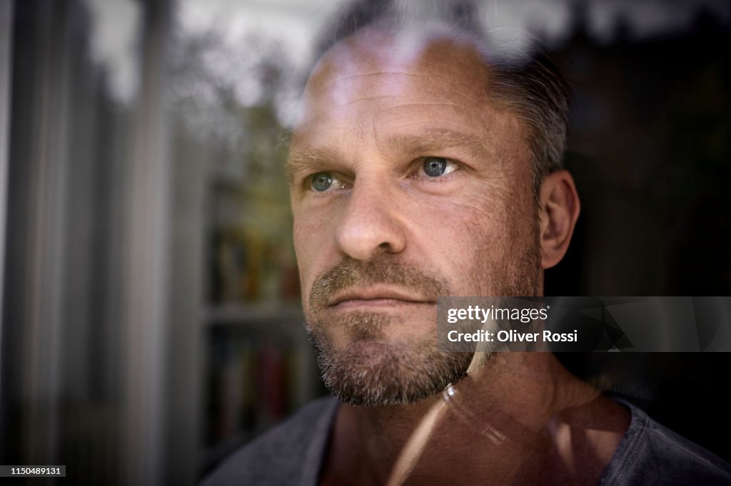 Portrait of mature man looking through window