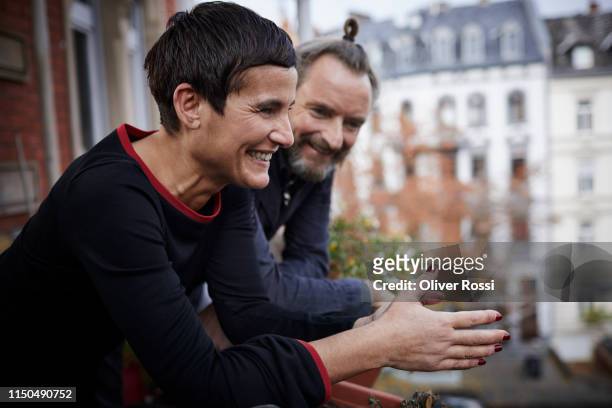 happy mature couple on balcony at home - leben in der stadt stock-fotos und bilder