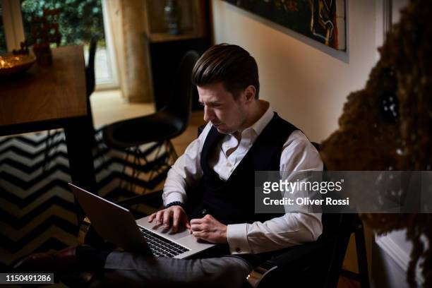 businessman sitting in armchair using laptop - premium access image only stock-fotos und bilder