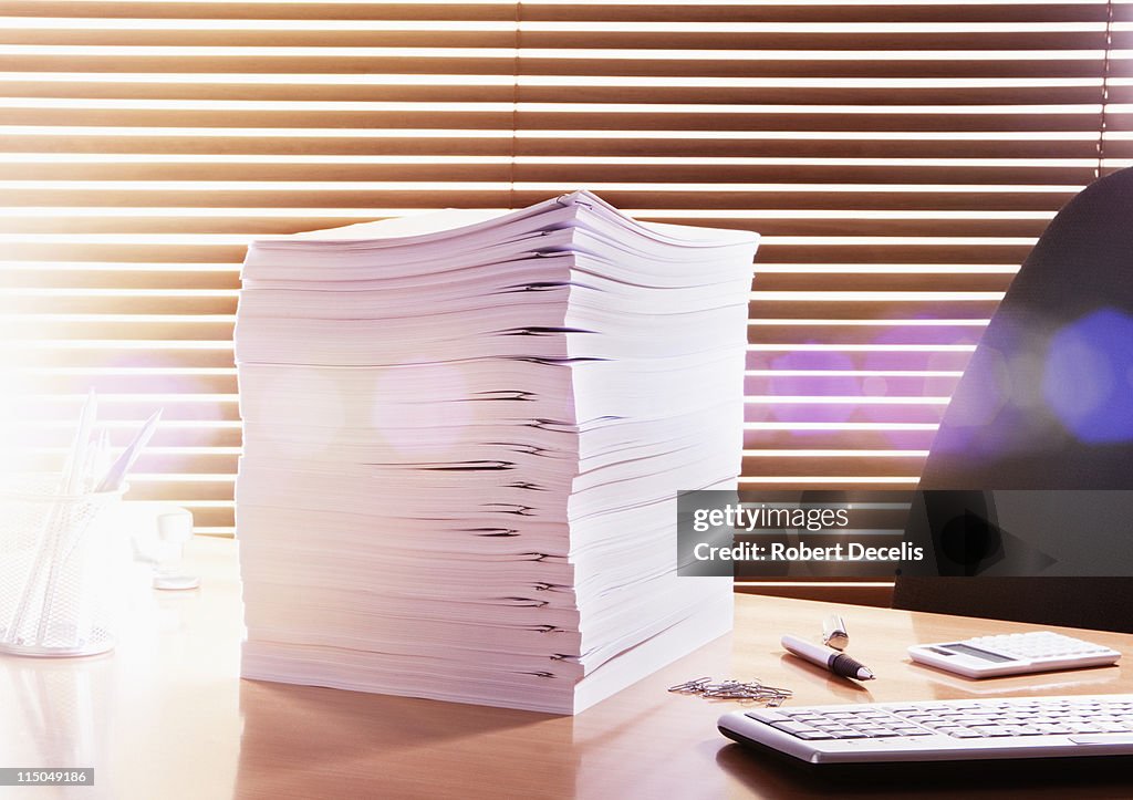 Large pile of documents on office desk.