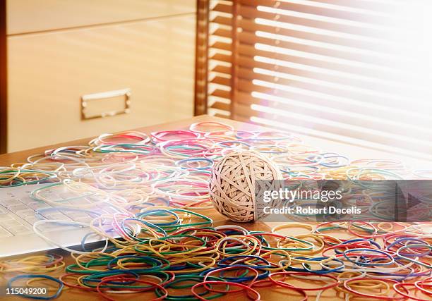 rubber band ball surrounded by colour rubber bands - elastic band ball stock pictures, royalty-free photos & images