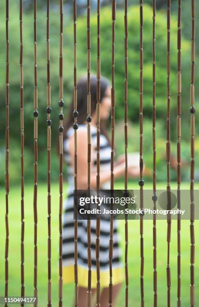 young woman standing in a garden - bead curtain stock pictures, royalty-free photos & images