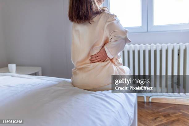 la mujer siente dolor de espalda masajeando dolores musculares - sciatic nerve fotografías e imágenes de stock