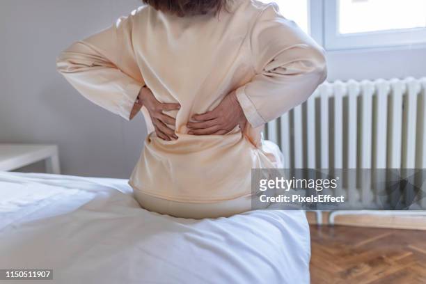 la femme ressent la douleur de dos massant les muscles douloureux - sciatic nerve photos et images de collection