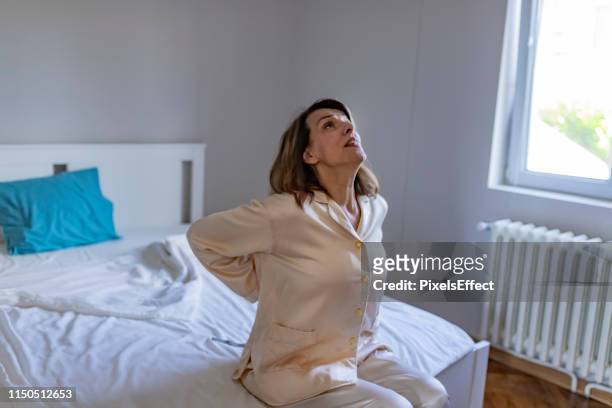 woman having lower back pain - back pain bed stock pictures, royalty-free photos & images