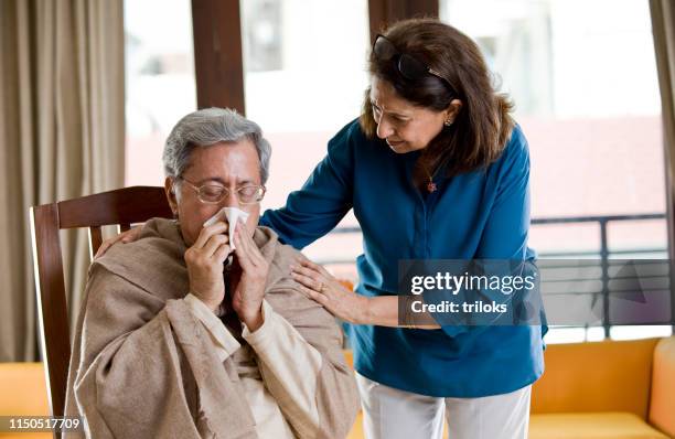 woman comforting husband sneezing at home - old cough stock pictures, royalty-free photos & images