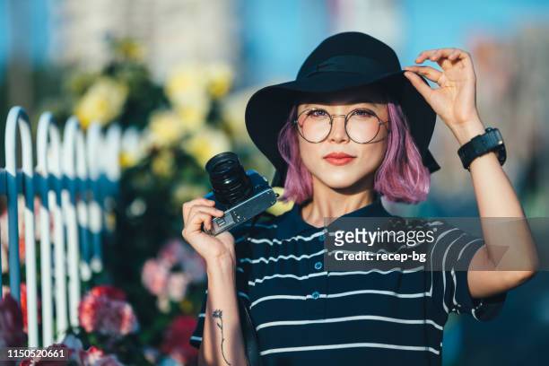 portrait of young and beautiful woman while holding camera - ladies hat stock pictures, royalty-free photos & images