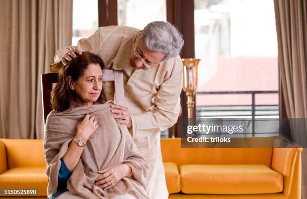 husband comforting old ailing wife at home - woman in a shawl stock pictures, royalty-free photos & images