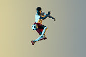 Male soccer player kicking ball in jump isolated on gradient background