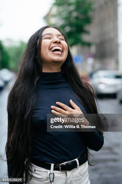 laughing portrait of queer hispanic woman - main sur la poitrine photos et images de collection