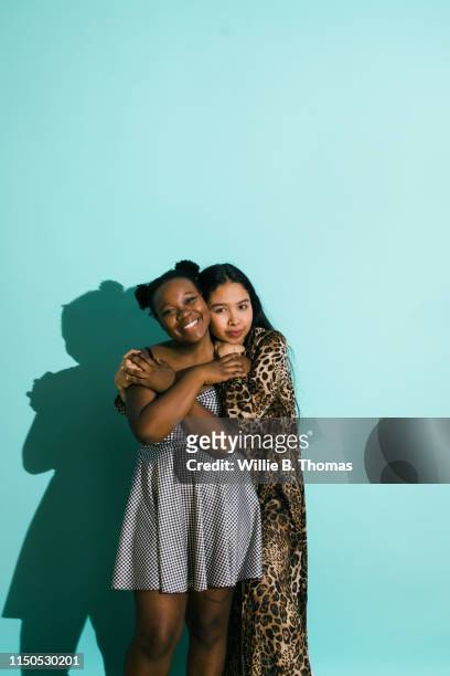 bisexual couple hugging on a turquoise background - women standing against grey background stock pictures, royalty-free photos & images