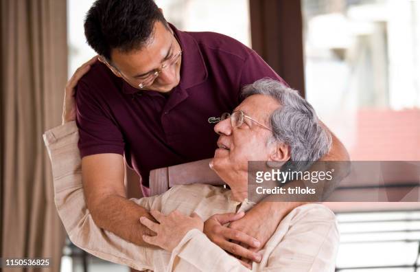 man spending time with his father at home - senior indian stock pictures, royalty-free photos & images