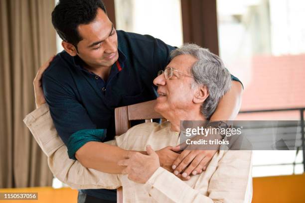 man spending time with his father at home - father stock pictures, royalty-free photos & images