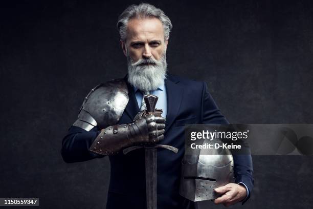 classy dressed senior businessman with knight sword - cavaleiro imagens e fotografias de stock