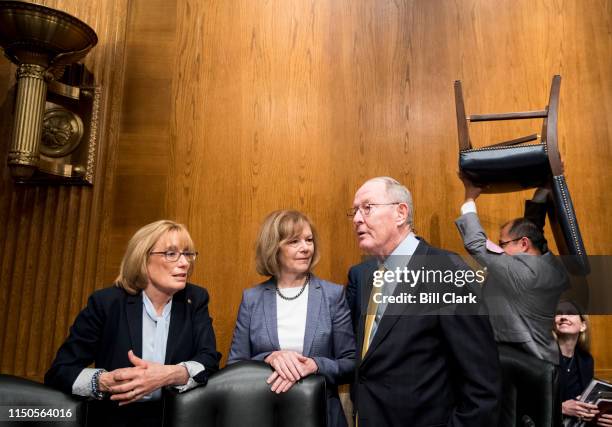 From left, Sen. Maggie Hassan, D-N.H., Sen. Tina Smith, D-Minn., and chairman Sen. Lamar Alexander, R-Tenn., talk as a staffer carries a chair behind...