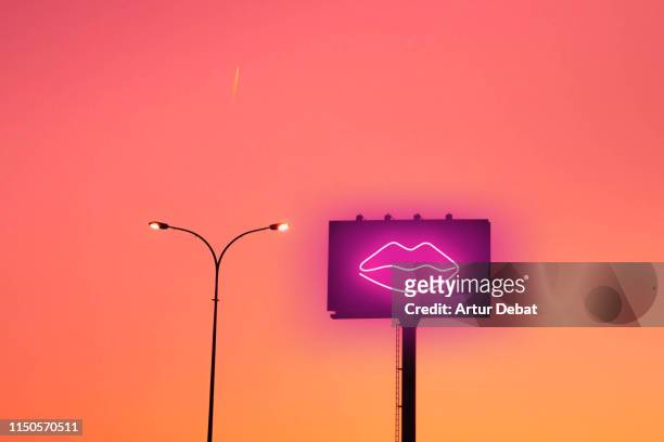 billboard with sexy lips neon light and sunset sky in the city. - sign pole stock pictures, royalty-free photos & images