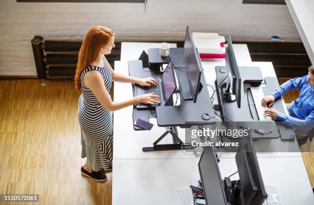 kvinna som arbetar på ergonomiskt stående skriv bord - ergonomics bildbanksfoton och bilder