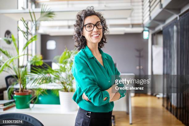 portrait of confident mature businesswoman in office - entrepreneur stock pictures, royalty-free photos & images