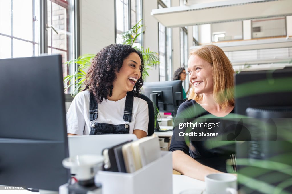 Lächelnde Kolleginnen arbeiten im Büro zusammen