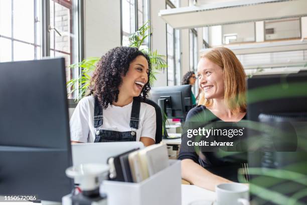 smiling female colleagues working together in office - happy colleague stock pictures, royalty-free photos & images