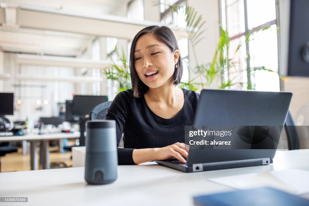 Profissional fêmea que usa o assistente virtual na mesa