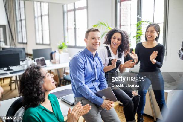 gente de negocios aplaudiendo por colega masculino en la oficina - applauding fotografías e imágenes de stock