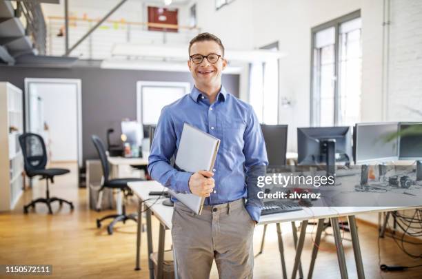 porträt des selbstbewussten geschäftsmannes im büro mit einem laptop - business portrait stehend stock-fotos und bilder