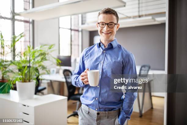 smiling male professional having coffee in office - holding coffee stock pictures, royalty-free photos & images