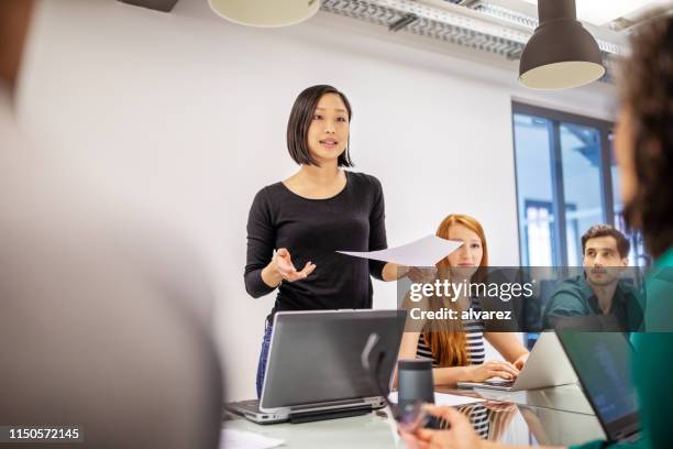 mujer profesional confiada discutiendo con colegas - presentación fotografías e imágenes de stock