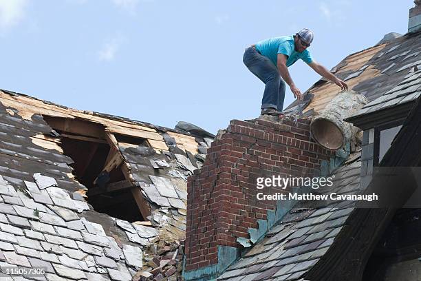 Worker removes debris from the roof of a tornado-damaged building on the campus of the The MacDuffie School June 2, 2011 in Springfield,...