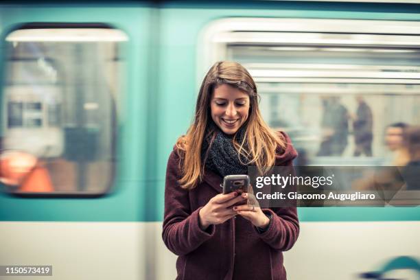 young woman texting at the phone in the underground station, paris, france. - plan metro photos et images de collection