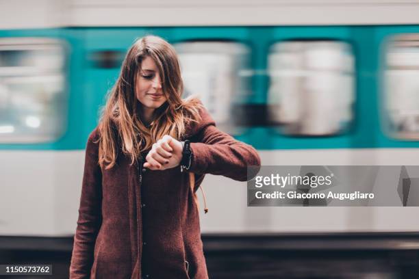 young woman watching her wristwatch in the underground station, paris, france. - tijdmeter stockfoto's en -beelden