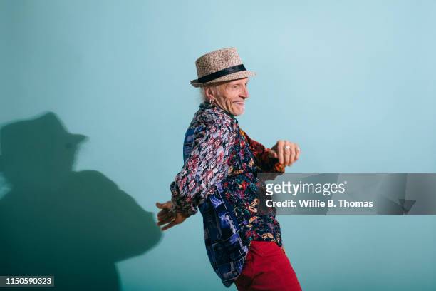 senior gay man in colorful shirt dancing - 69 pose stock-fotos und bilder