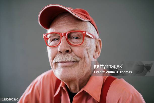 portrait of senior gay man wearing red glasses - gente común y corriente fotografías e imágenes de stock