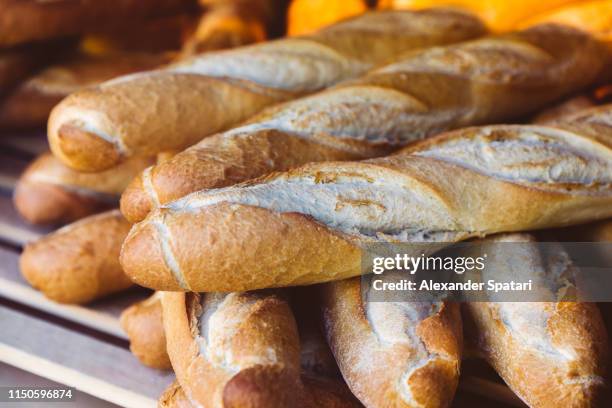 fresh bread baguettes in the bakery, close-up - barra de pan francés fotografías e imágenes de stock