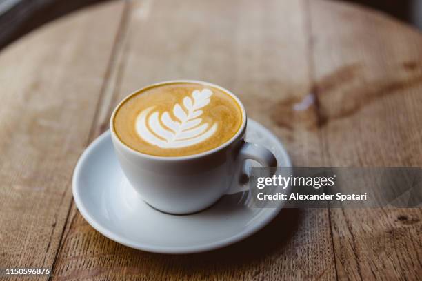 cup of cappuccino on a wooden table, close up - latte stock pictures, royalty-free photos & images