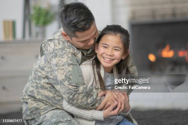 military dad hugging his young daughter - filipino family reunion stock pictures, royalty-free photos & images