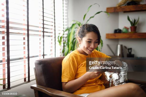 woman using her smart phone at home - östasiatiskt ursprung bildbanksfoton och bilder