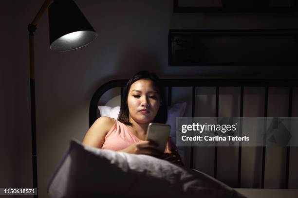 woman texting in bed late at night - dating stockfoto's en -beelden